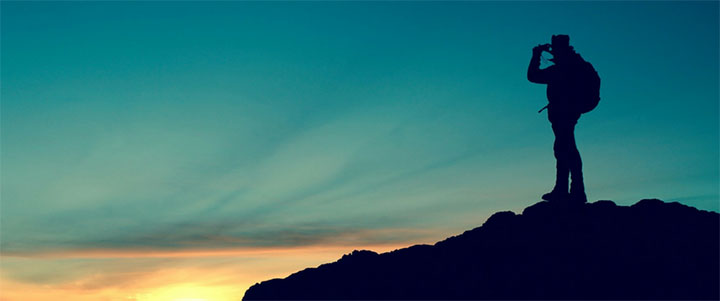 silhouette of a man on a mountain at dusk